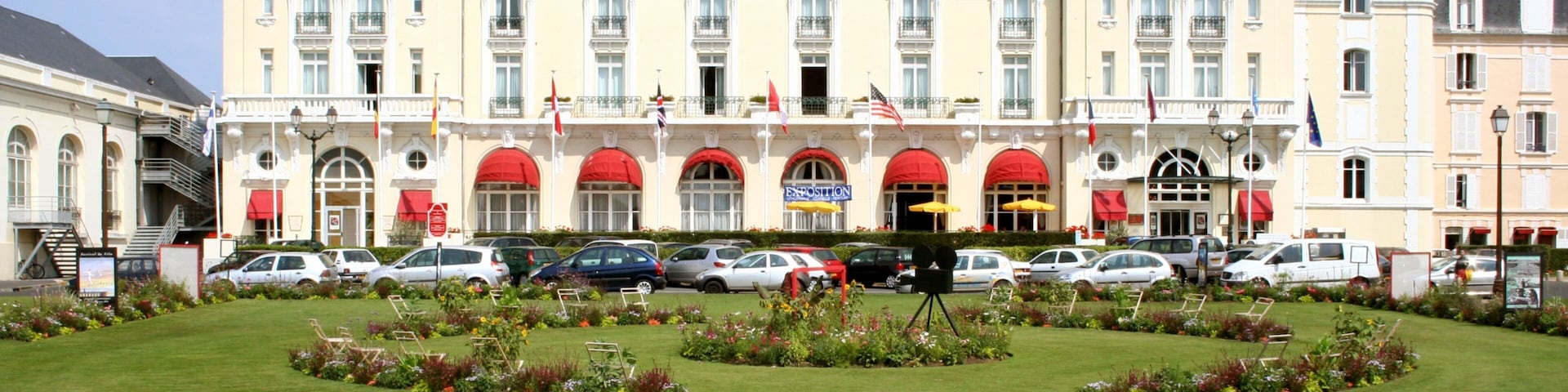 A large hotel with a garden in front.