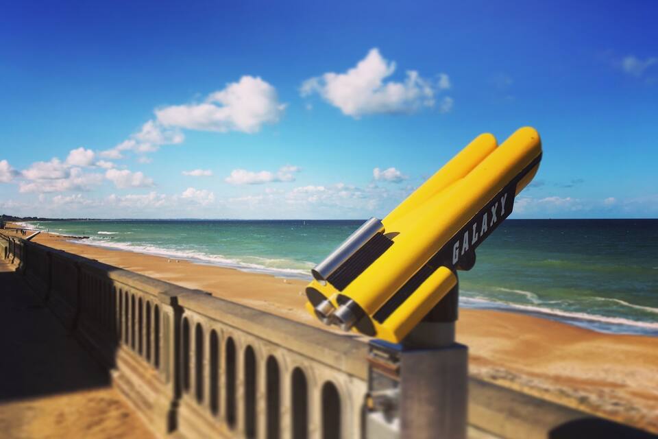 A yellow object with the word "GALAXY" on it, leaning against a railing by the ocean.
