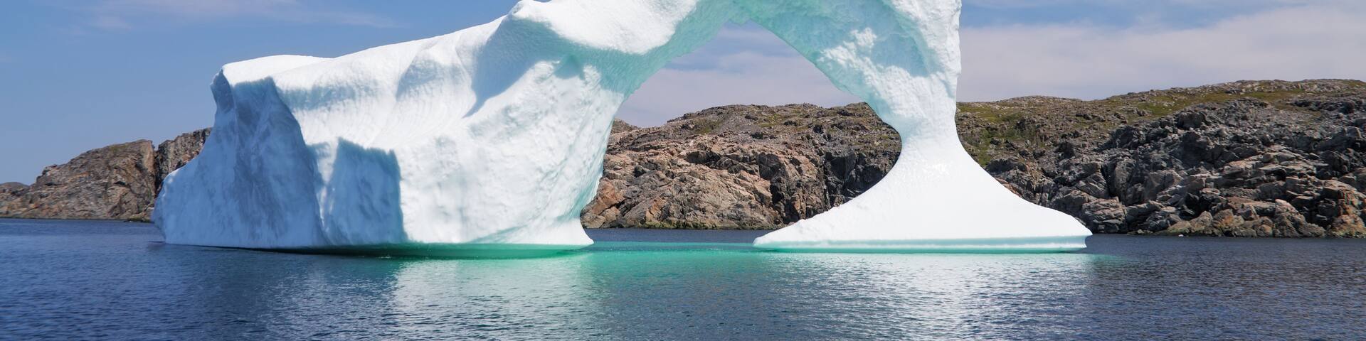 Iceberg in front of a rocky island, Newfoundland and Labrador