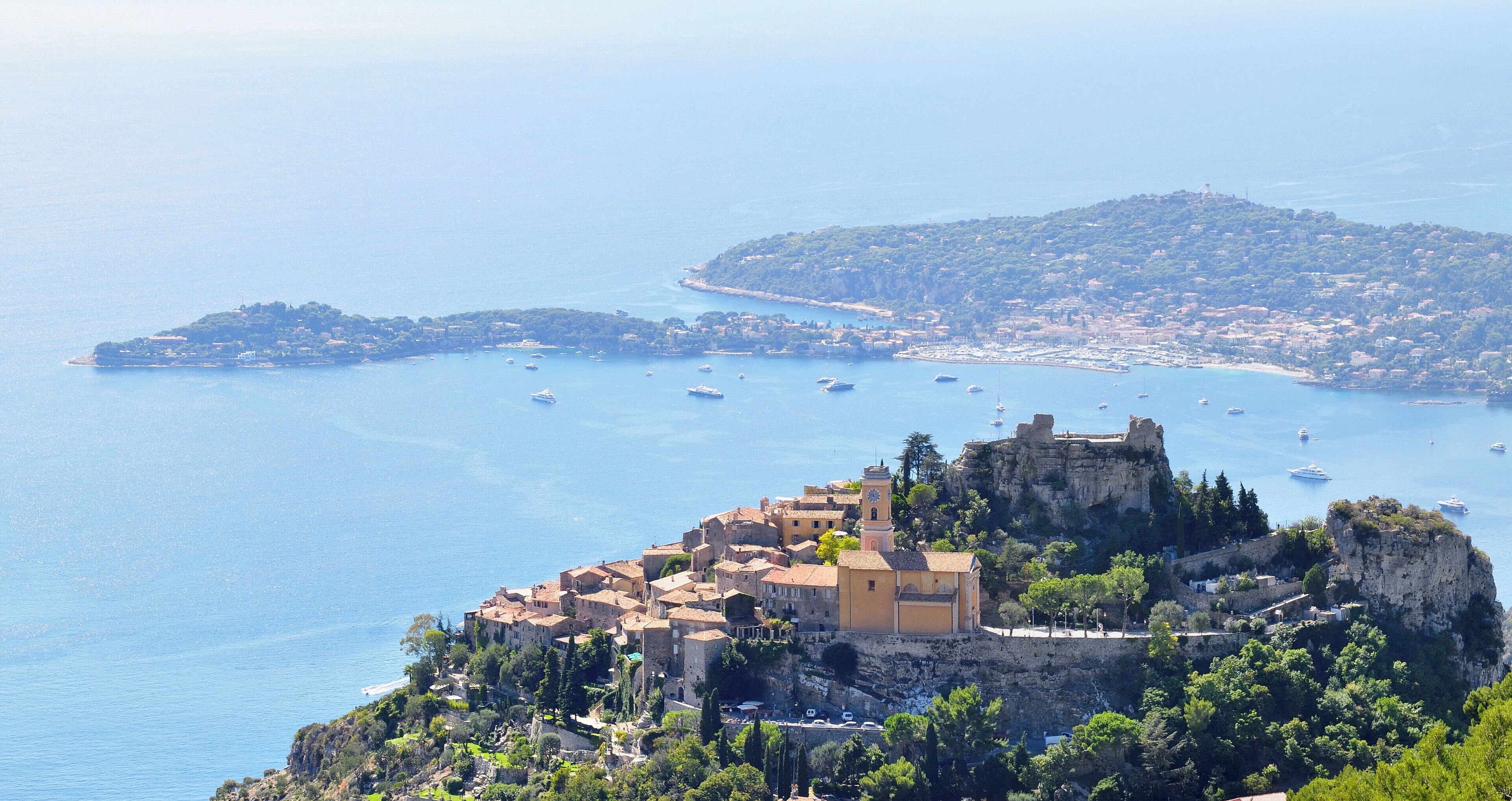A coastal town with historic buildings, a prominent church, and a castle on a cliff overlooking the sea.
