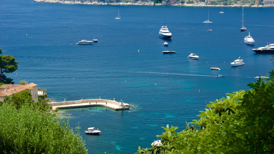 A marina with various boats, a stone pier, and lush greenery.