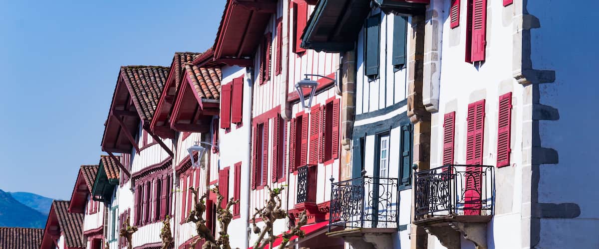 A row of traditional European buildings with red shutters and white facades.