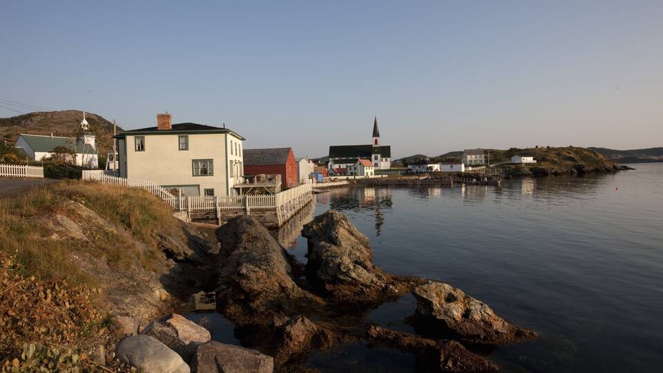 A coastal town with a prominent church, rocky shoreline, and traditional buildings.