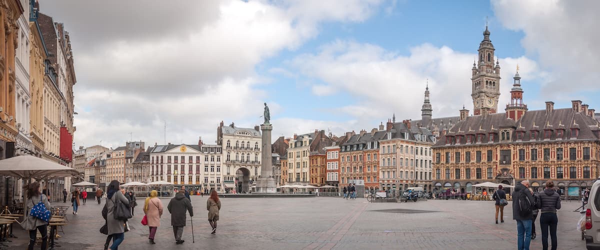 A historic square with ornate buildings, a prominent clock tower, and a central monument.
