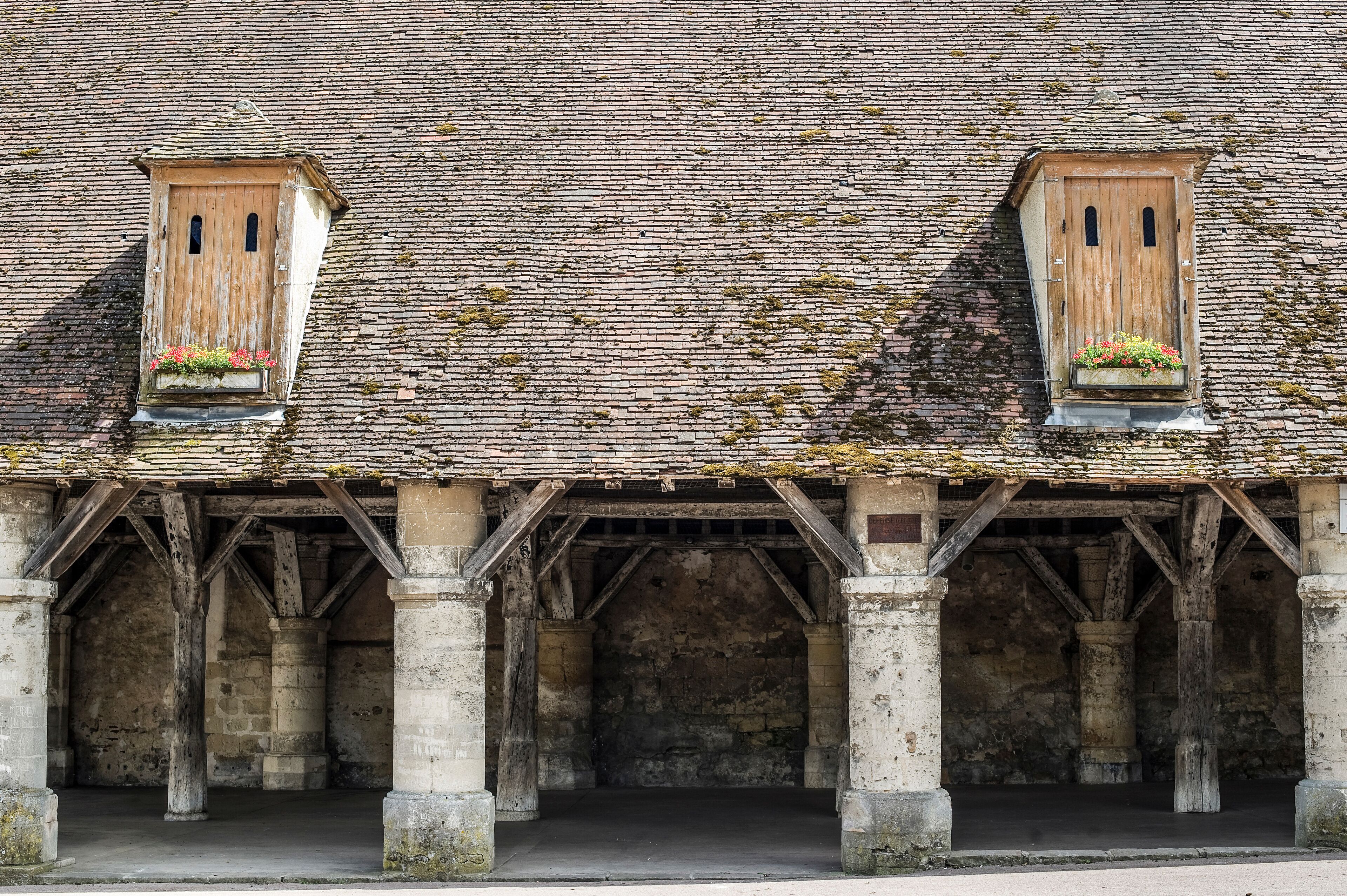 A historic building with two wooden dormer windows, each with a flower box.