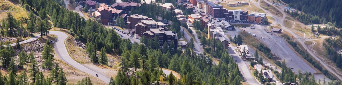 A mountainous town with winding roads, dense forests, and a mix of residential and commercial buildings.
