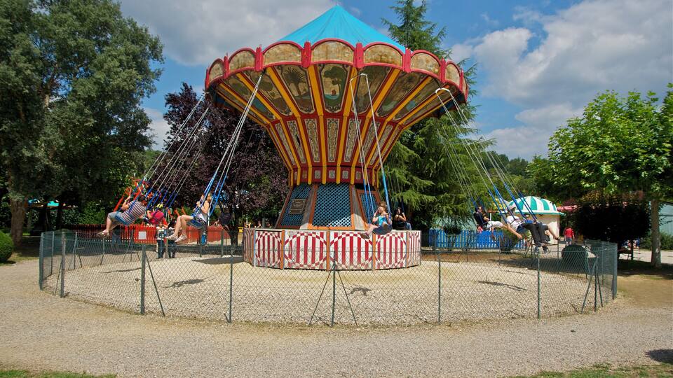 A carousel with a blue canopy and red and yellow stripes, surrounded by a fence.
