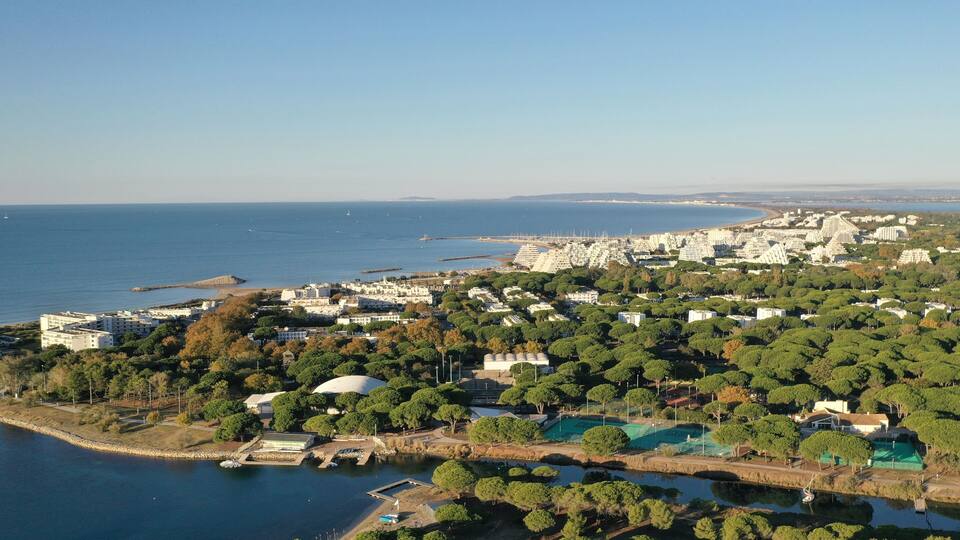 A coastal cityscape with dense residential buildings, a marina, and a large body of water.