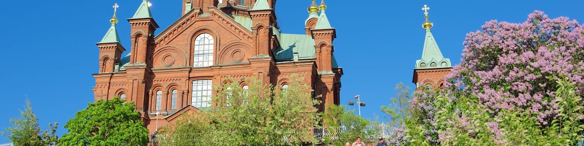 A large red brick church with green domes and golden crosses.