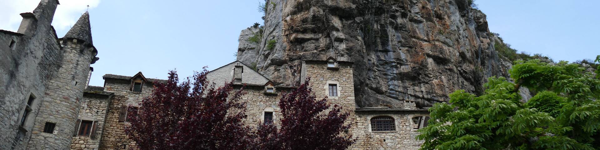 A historic stone building with a prominent rock formation in the background.