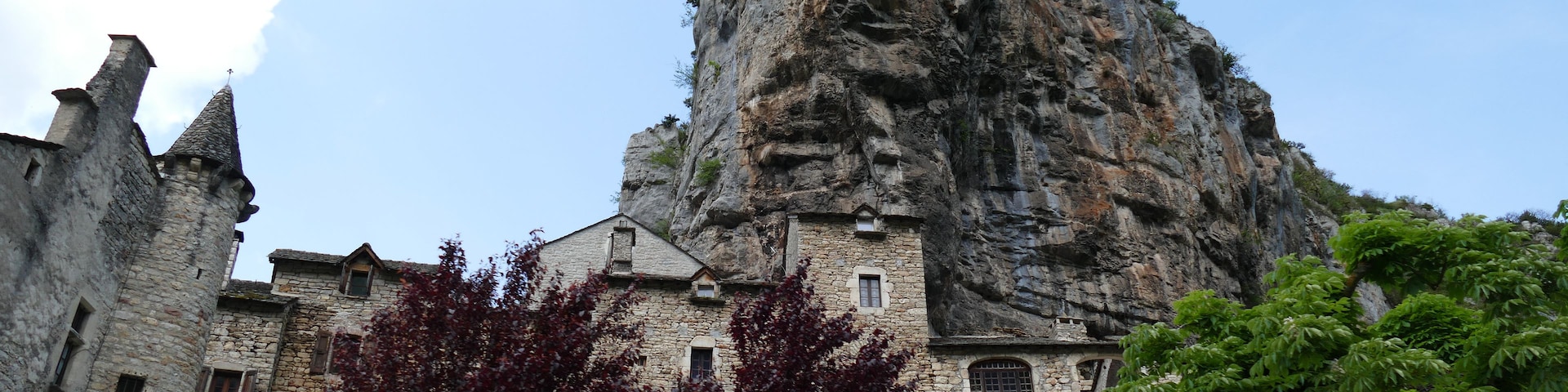 Ein historisches Steinhaus mit einer markanten Felsformation im Hintergrund.