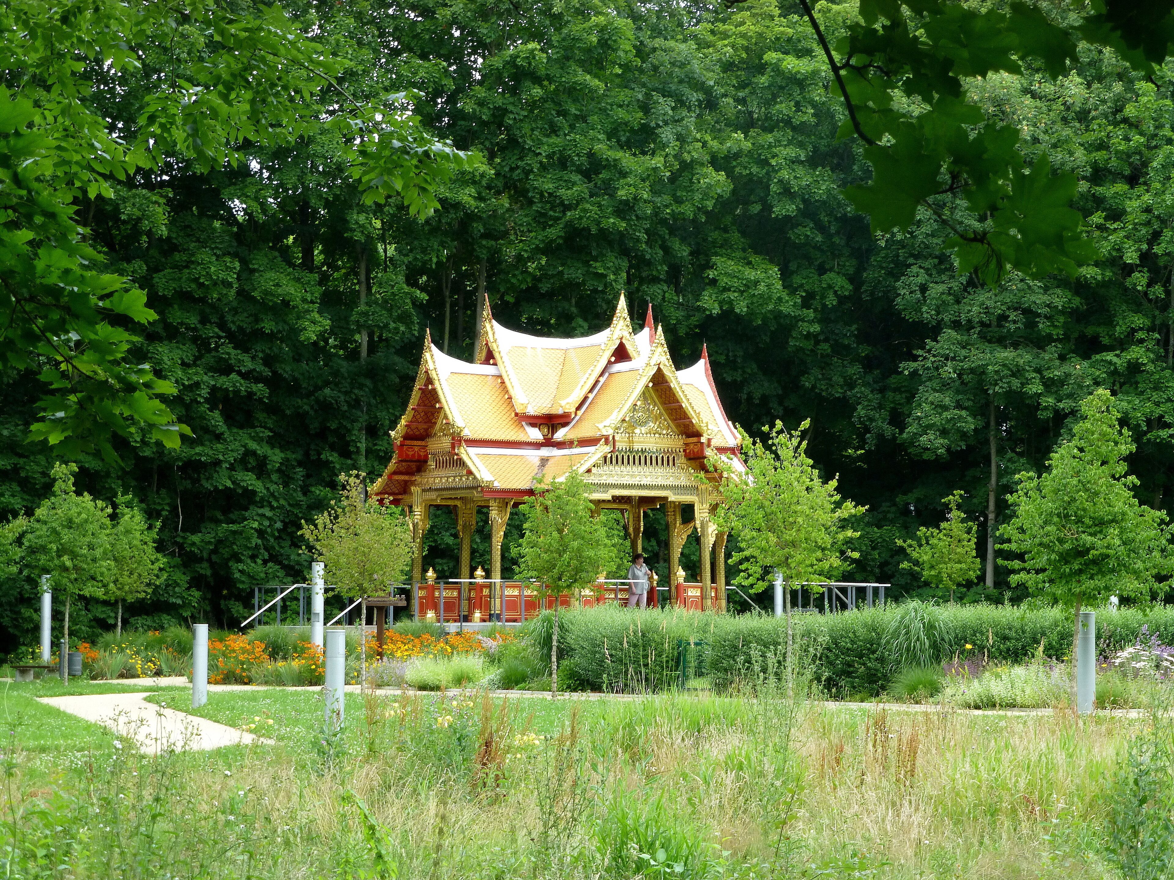 A traditional Thai temple surrounded by lush greenery and a well-maintained garden.