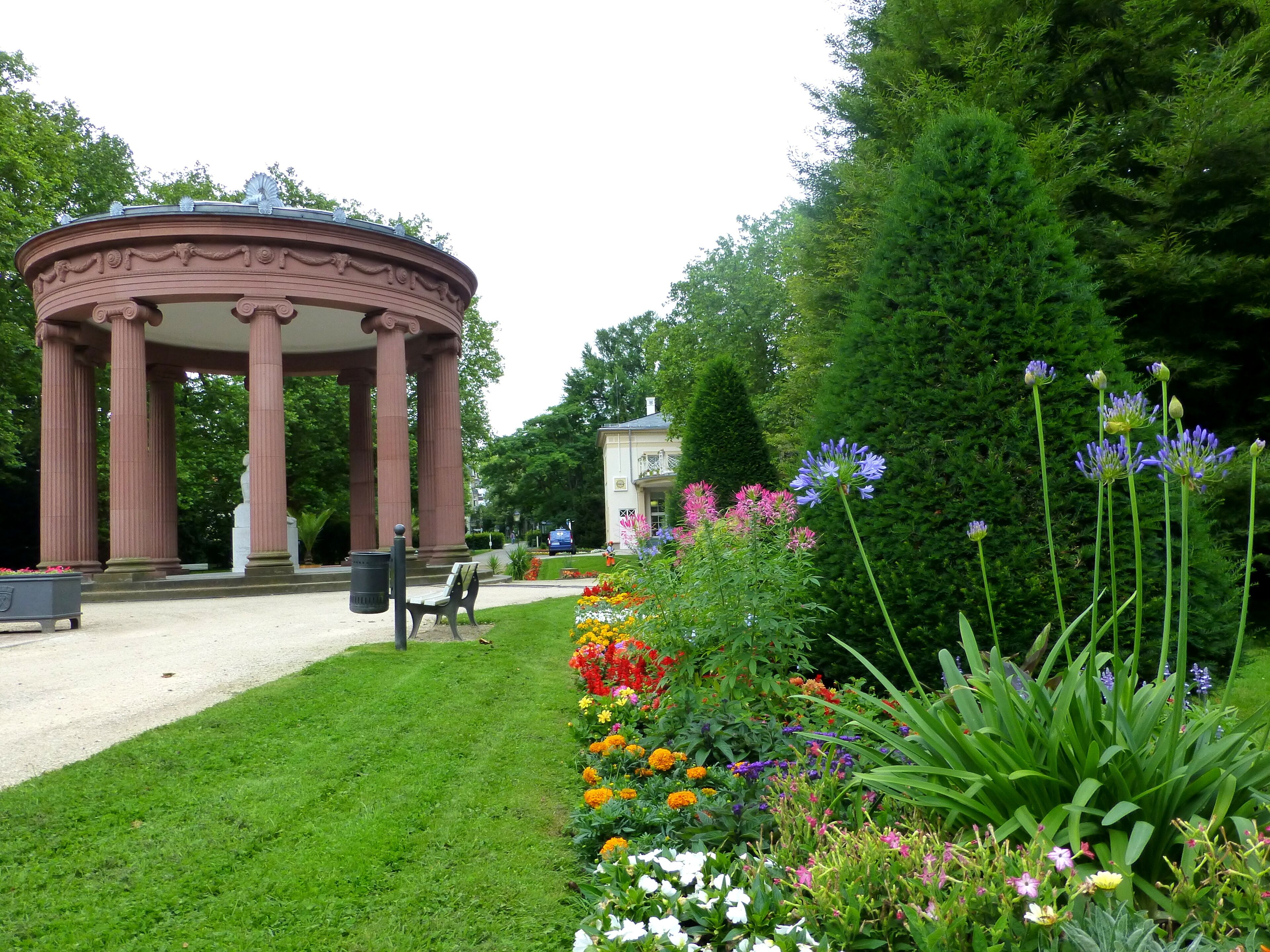 A garden with a pavilion, a statue, and a variety of colorful flowers.