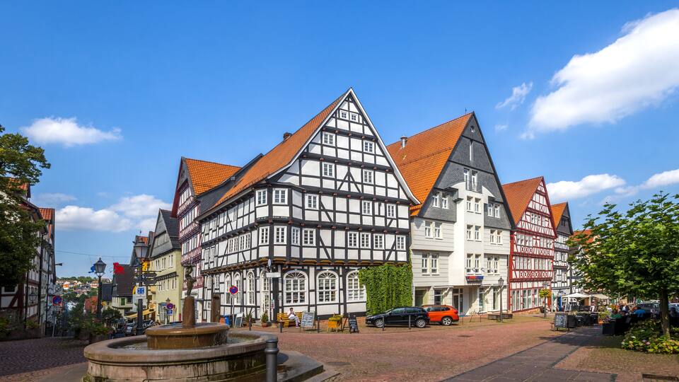 A traditional half-timbered building with a fountain in the foreground.