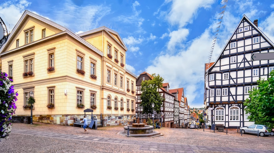 A cobblestone square with historic buildings, including a yellow building with arched windows and a half-timbered structure.