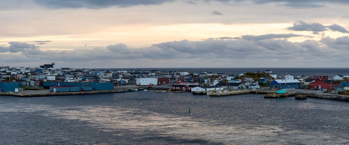 A coastal town with a harbor, houses, and a lighthouse.
