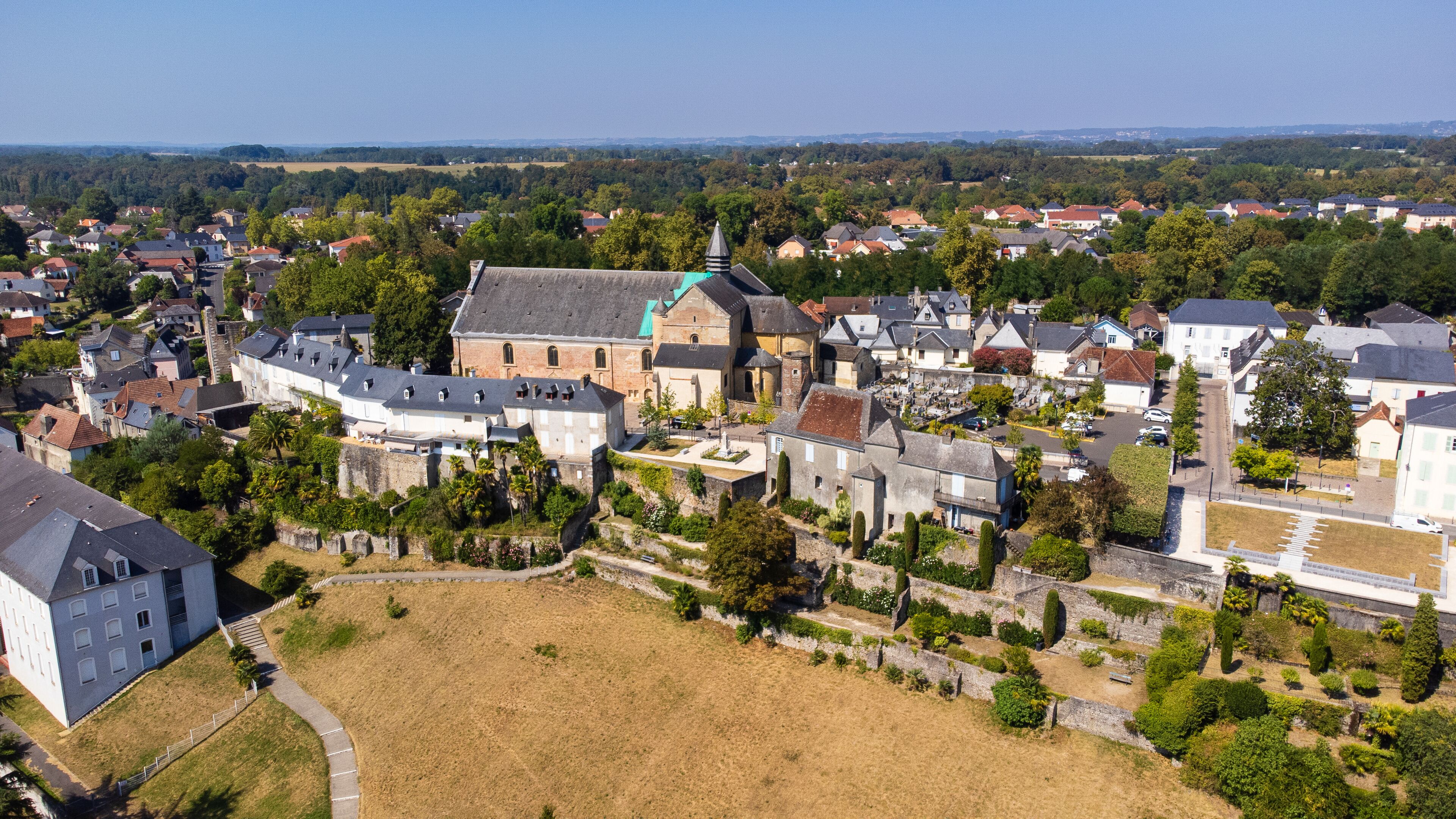 An aerial view of a historic town with a prominent church, residential houses, and a large open field.