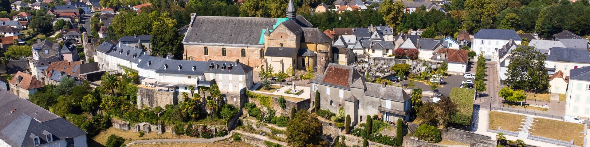 An aerial view of a historic town with a prominent church, residential houses, and a large open field.