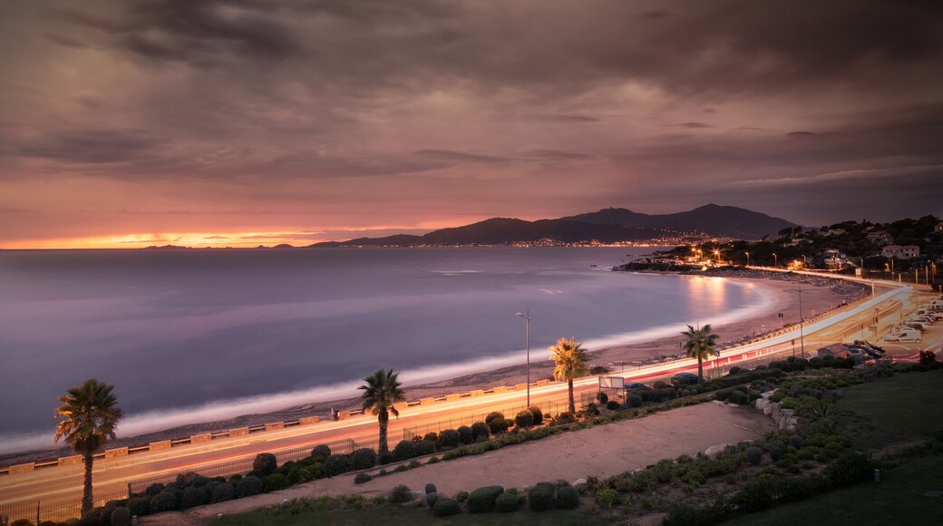 Slow shutter image of car light trails along the beach at Porticcio on the west coast of Corsica with the sun setting behind les Iles Sanguinaire near Ajaccio under a dark stormy sky, Shutterstock ID 720528625, Purchase Order: -