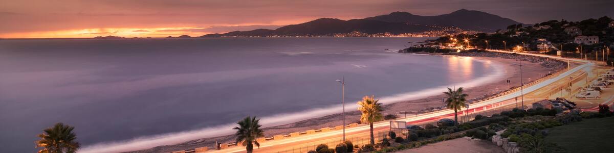 Slow shutter image of car light trails along the beach at Porticcio on the west coast of Corsica with the sun setting behind les Iles Sanguinaire near Ajaccio under a dark stormy sky, Shutterstock ID 720528625, Purchase Order: -