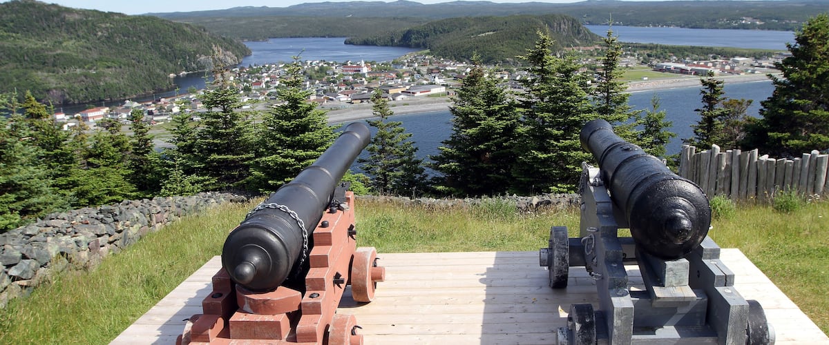Two cannons on a wooden platform overlooking a lake and town.