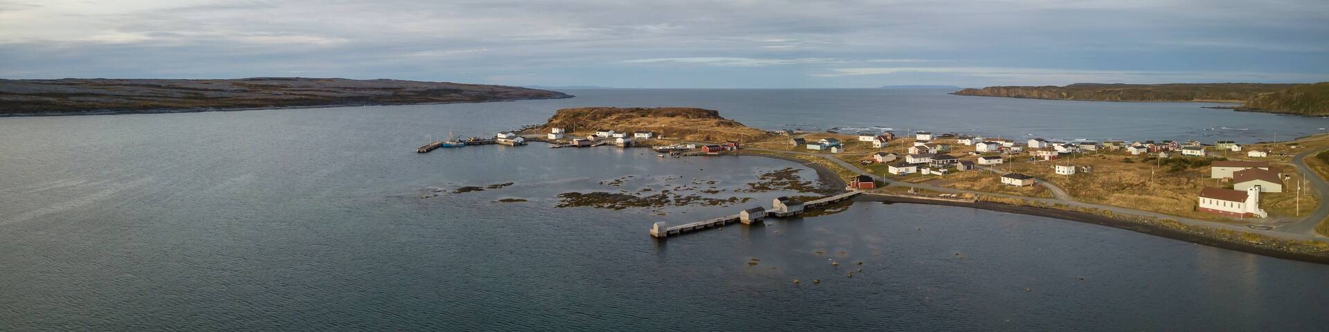 Aerial panoramic view of a small town on a rocky Atlantic Ocean Coast during a cloudy day. Taken in Raleigh, Newfoundland, Canada.