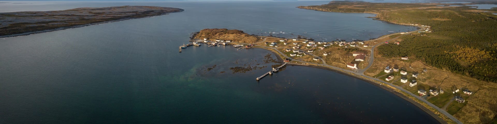 Aerial panoramic view of a small town on a rocky Atlantic Ocean Coast during a cloudy day. Taken in Raleigh, Newfoundland, Canada.