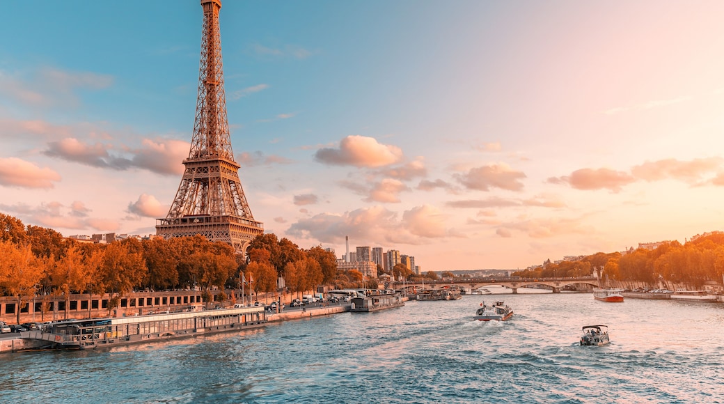 The main attraction of Paris and all of Europe is the Eiffel tower in the rays of the setting sun on the bank of Seine river with cruise tourist ships