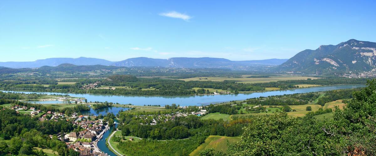 A river winding through a town surrounded by mountains and greenery.