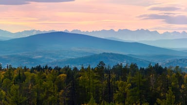 Wide angle panorama autumn forest,misty hills mountain tops in pink dawn