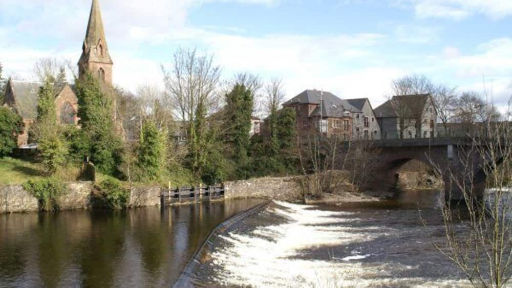 Ein Fluss mit einer Schleuse, einer Kirche und einer Brücke.