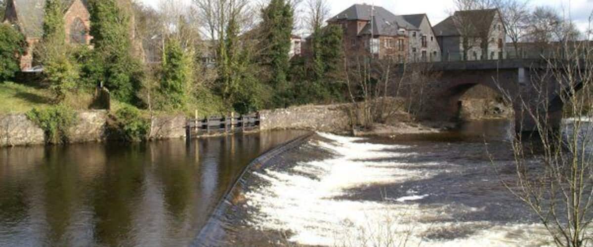A river with a lock, a church, and a bridge.