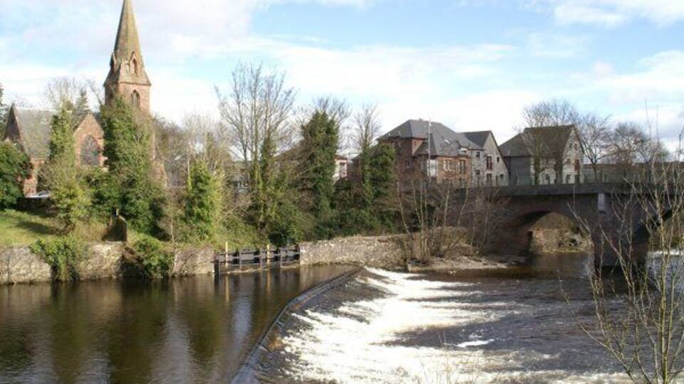 A river with a lock, a church, and a bridge.