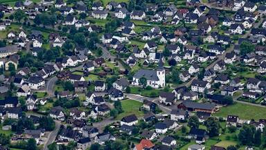 Una zona residencial densamente poblada con casas blancas, una iglesia y campos verdes circundantes.