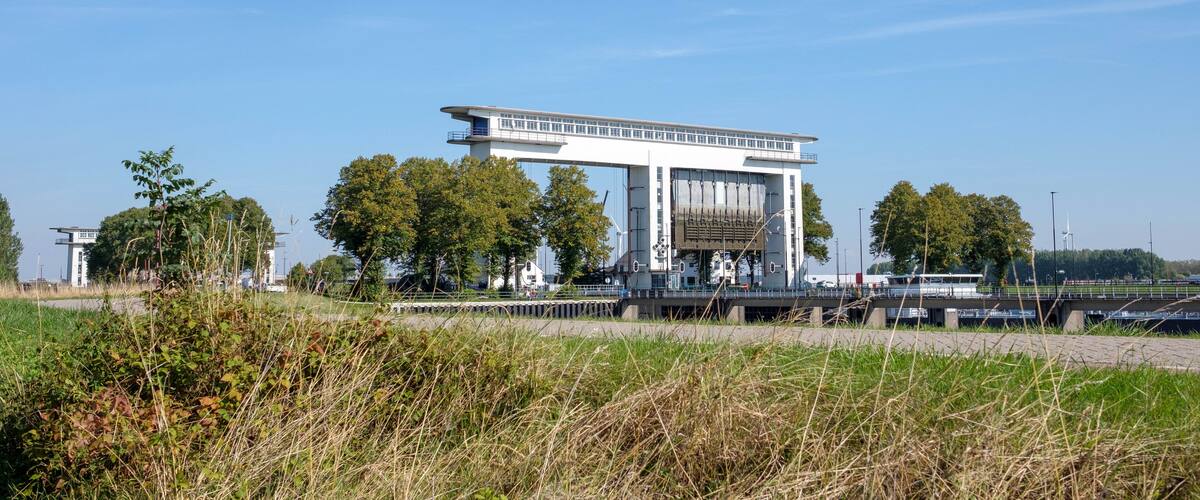 A modern building with a flat roof and large windows, surrounded by trees and a grassy area.