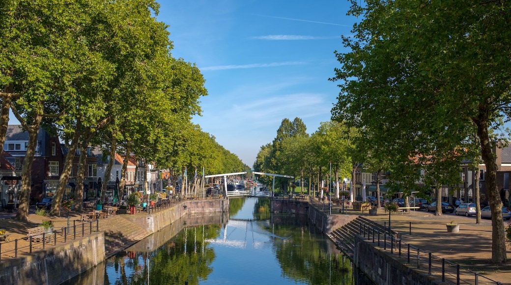 Un canal con un puente, bordeado de árboles y edificios.