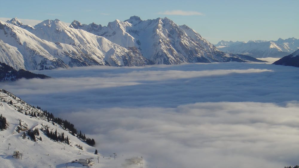 Une chaîne de montagnes enneigées surplombant une vallée de nuages.