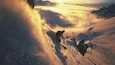 A skier descending a snow-covered mountain slope with clouds below.