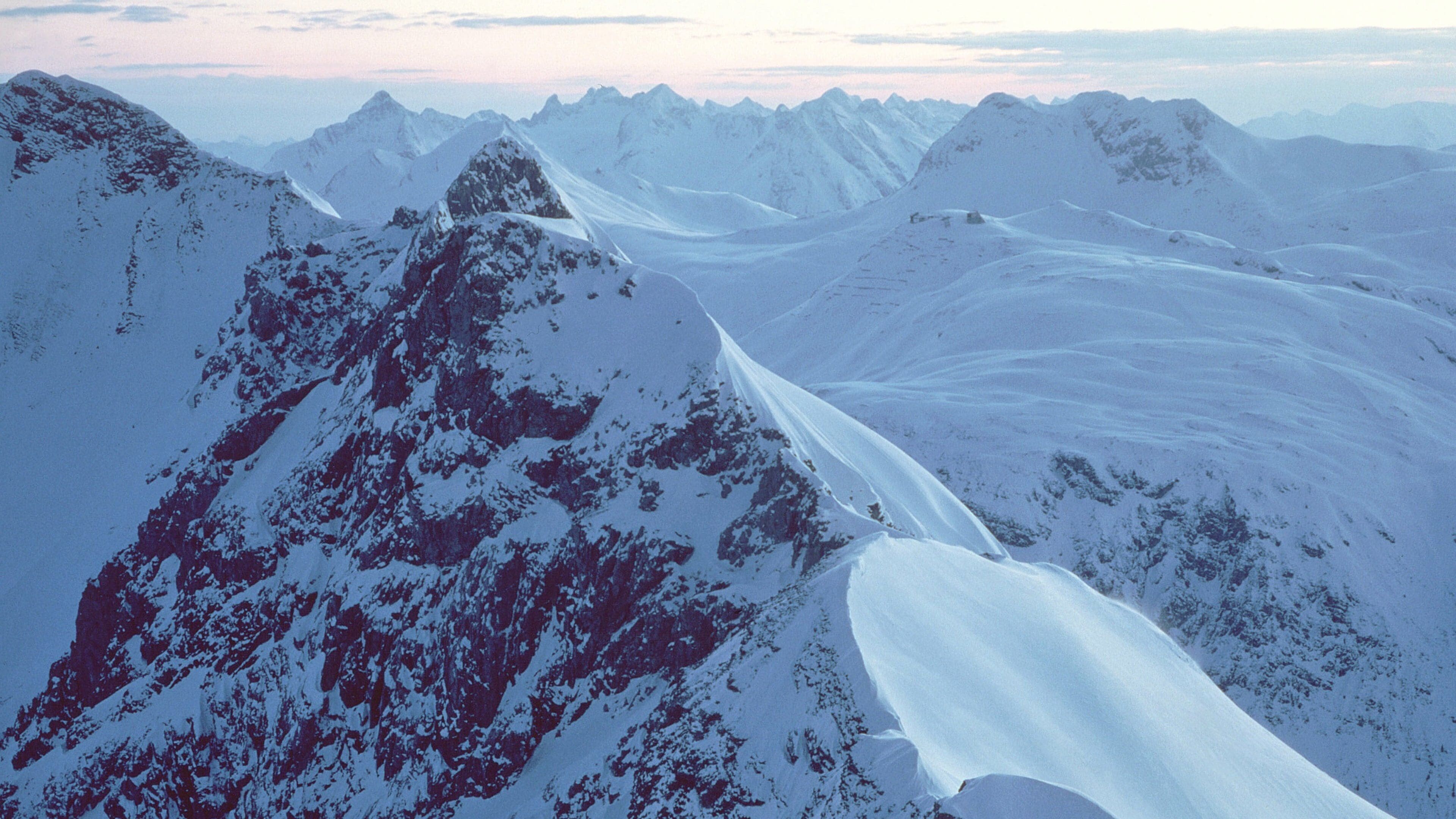 A snow-covered mountain range with sharp peaks and ridges.