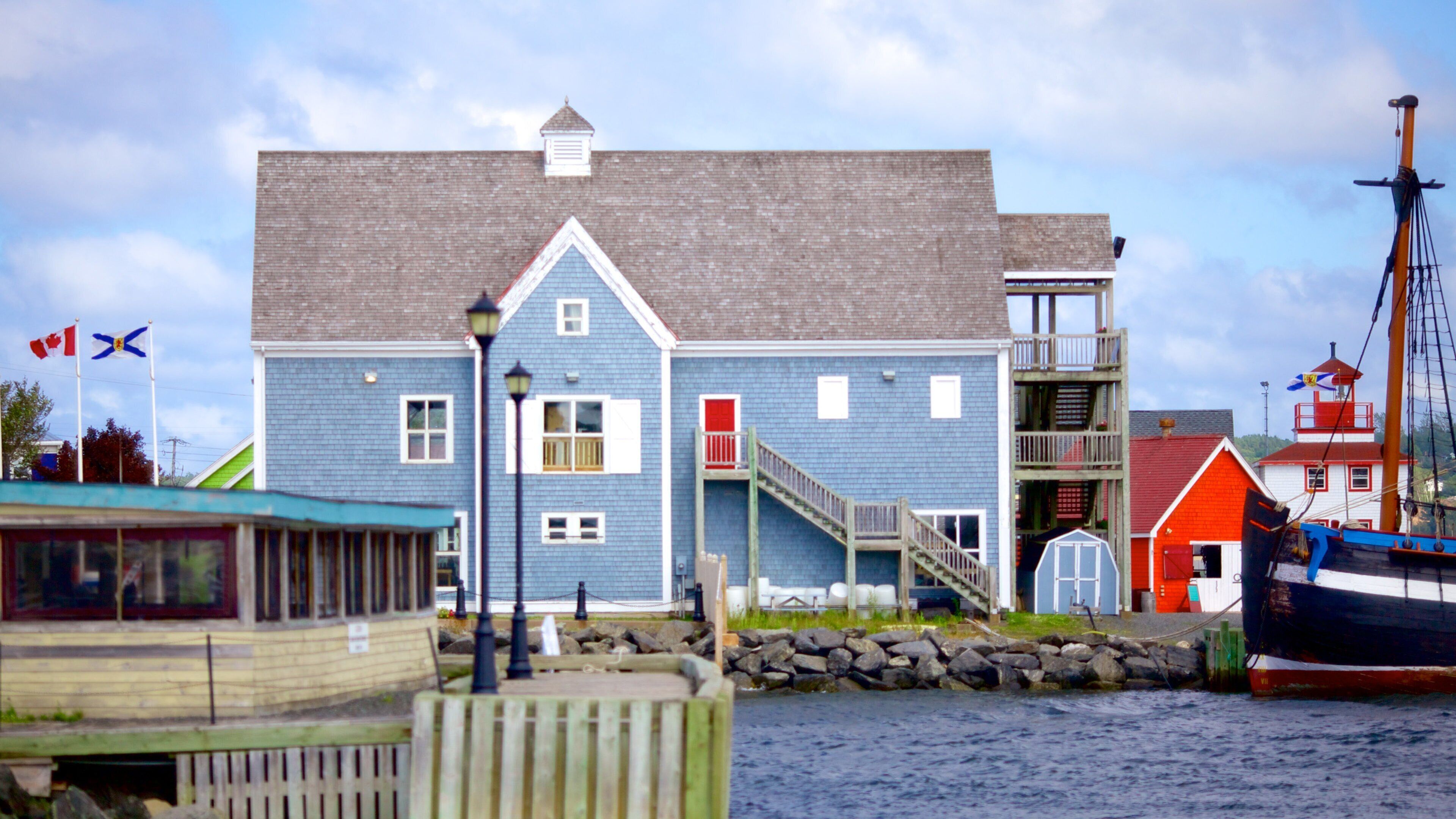 A blue building with a red door, a staircase, and a dock with boats.