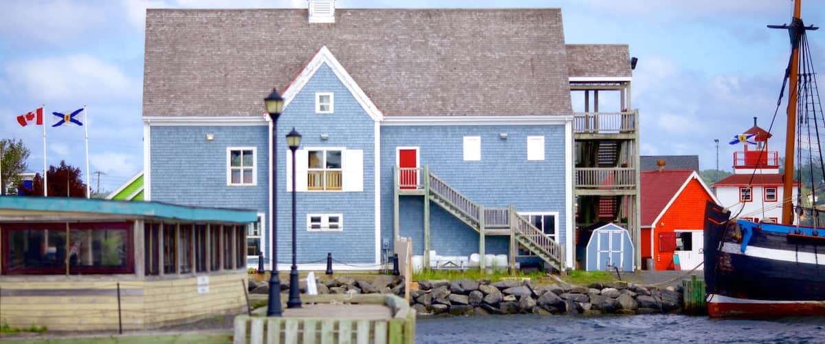 A blue building with a red door, a staircase, and a dock with boats.