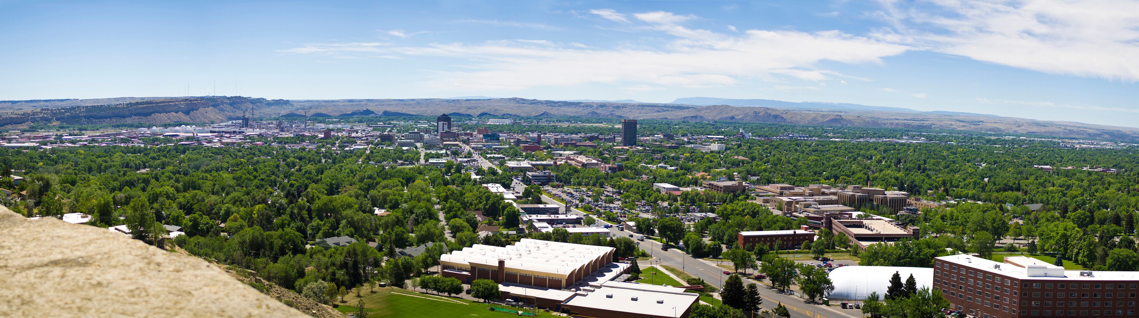 A cityscape with a large industrial area, a central business district, and surrounding green hills.