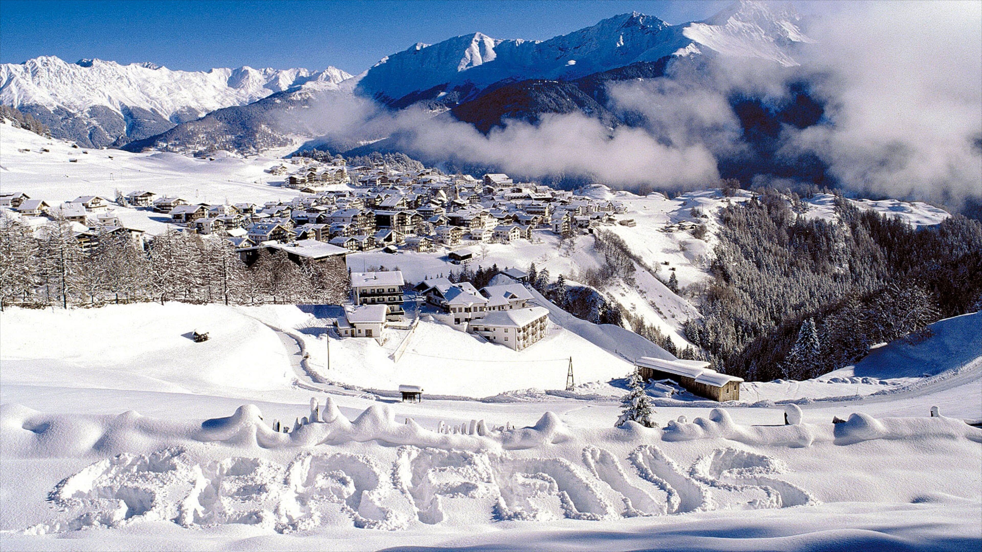 A snow-covered village with houses and a mountain backdrop.