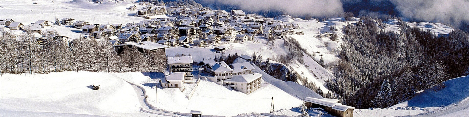 A snow-covered village with houses and a mountain backdrop.