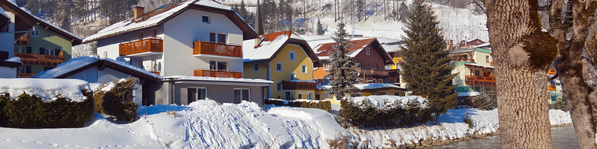 A snow-covered river with houses and mountains in the background.