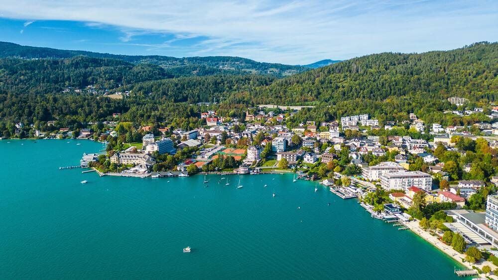 Une ville côtière dotée d’un port de plaisance, entourée de collines boisées.
