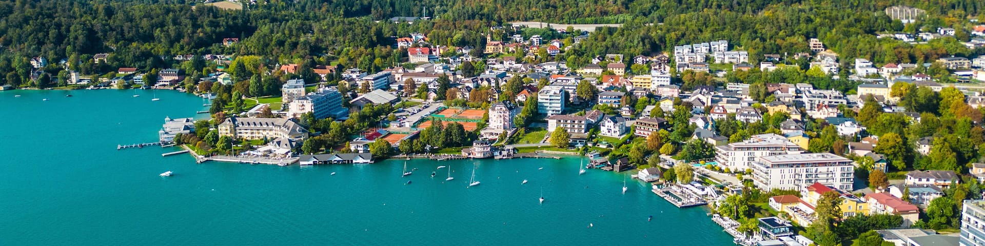 A coastal town with a marina, surrounded by forested hills.
