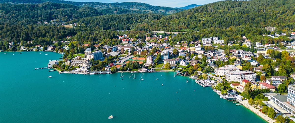 A coastal town with a marina, surrounded by forested hills.