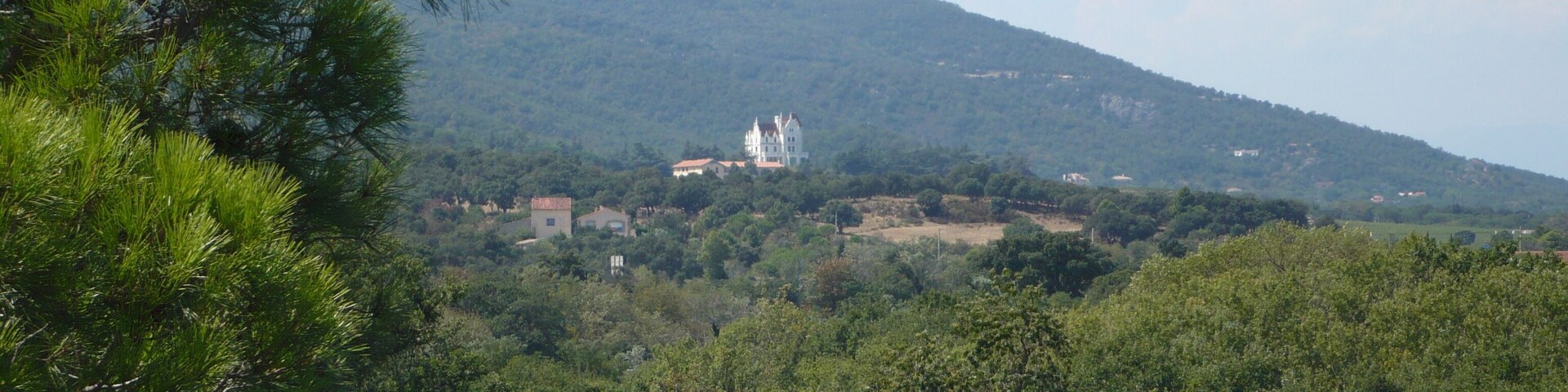 Un paysage montagneux avec une église blanche et plusieurs bâtiments situés sur une colline.