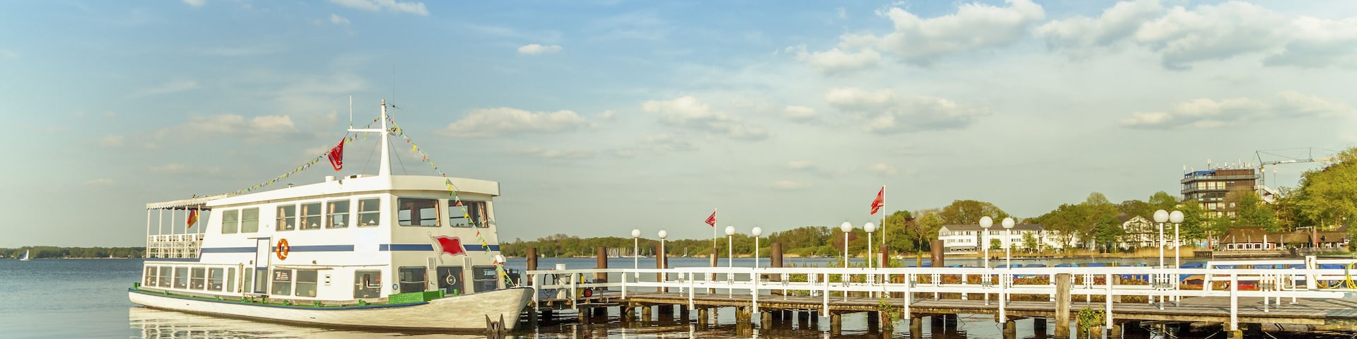 A riverboat docked at a pier with a cityscape in the background.